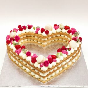 Dreischichtige Herztorte aus Keks und Buttercremeupfen, Macarons, frischen Himbeeren und Rosen